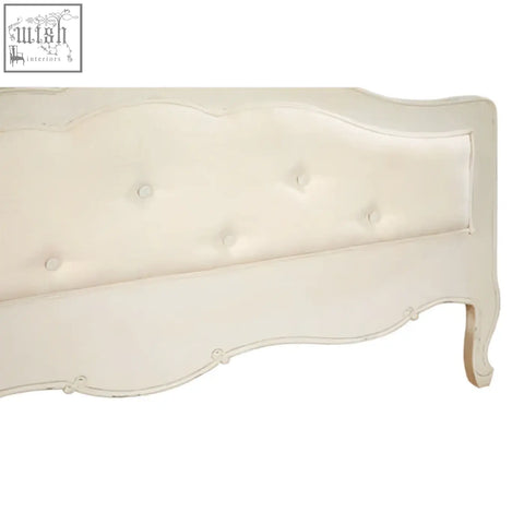 Cream-colored tufted headboard with soft upholstery and curved wooden frame on a loire white double bed