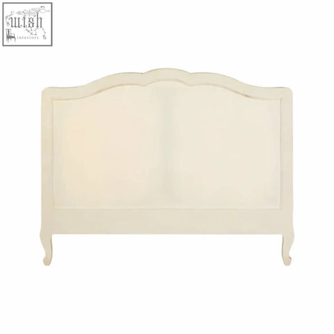Cream-colored upholstered headboard with curved top and ornate wooden frame on a loire white double bed
