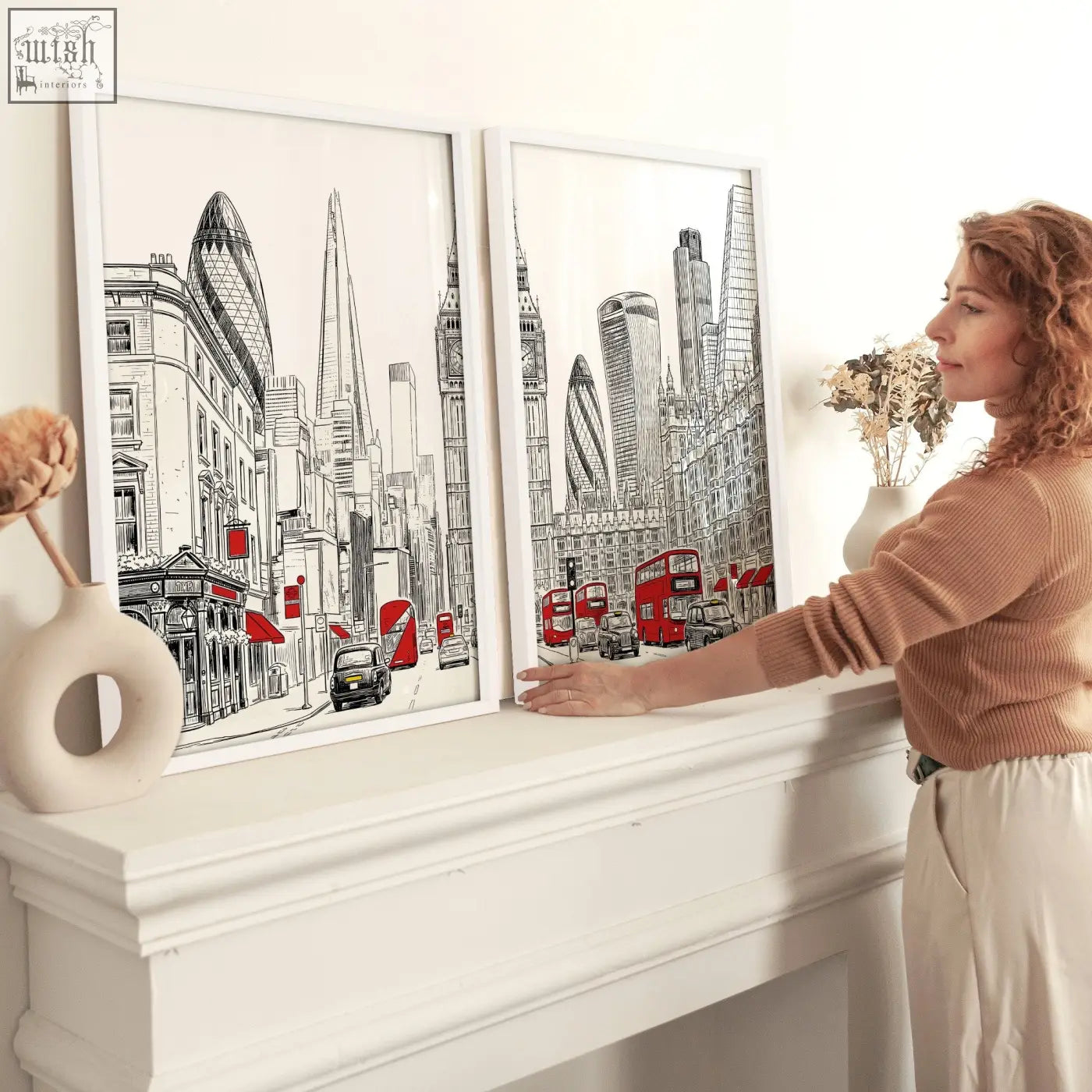 Two framed london abstract art prints featuring black white red city skyline with buses and taxis on a mantelpiece