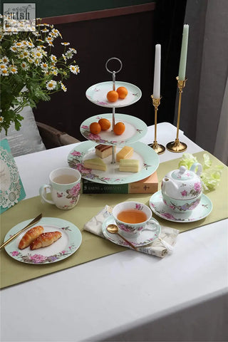 Delicate london boutique porcelain tiered cake stands with floral bird butterfly pattern holding oranges on top tier