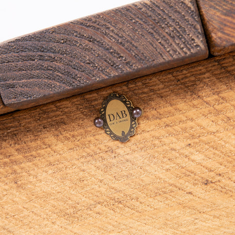Vintage-style oval metal plaque with ornate edges and dark gemstones on the dab chic stylish blanket box london side chest