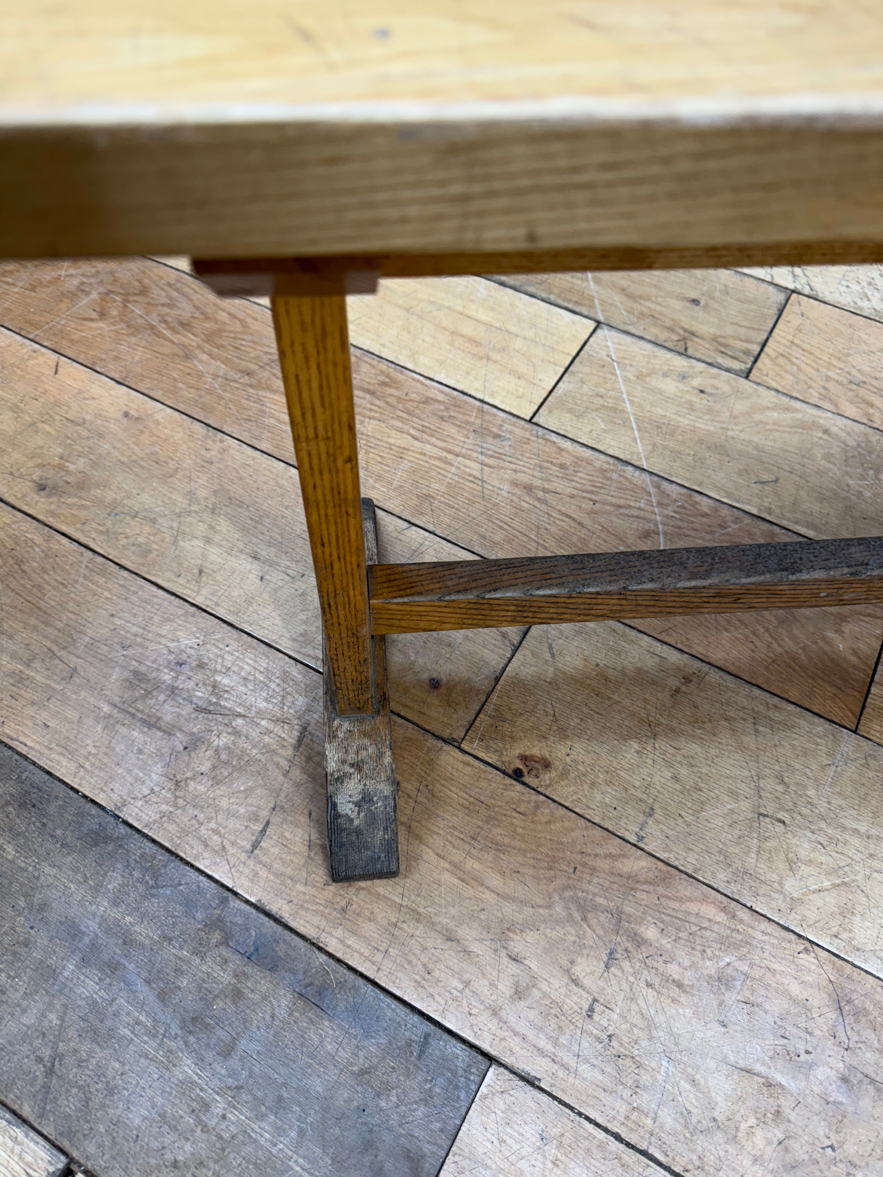 A rustic long vintage oak leys school bench with light wood finish and dark metal feet for hallway seating