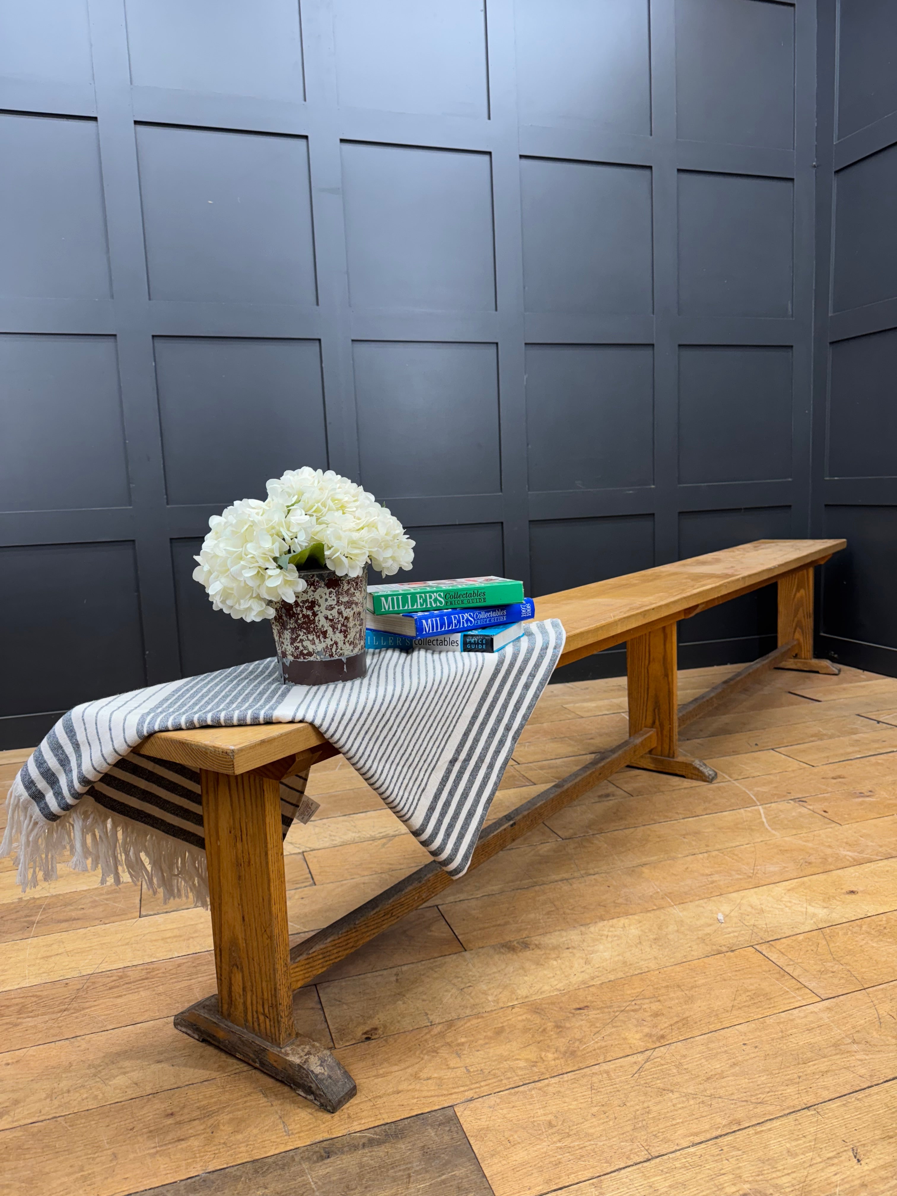 A long vintage oak school bench with rustic natural finish and sturdy angled legs ideal for leys school seating
