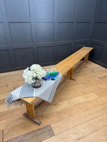Light-colored vintage oak school bench with simple rustic design and sturdy trestle legs perfect for leys school seating