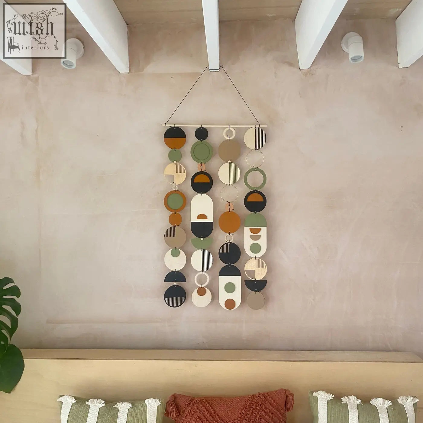 A modern hand painted wood wall art with geometric circular and oval shapes in earthy olive green and terracotta tones
