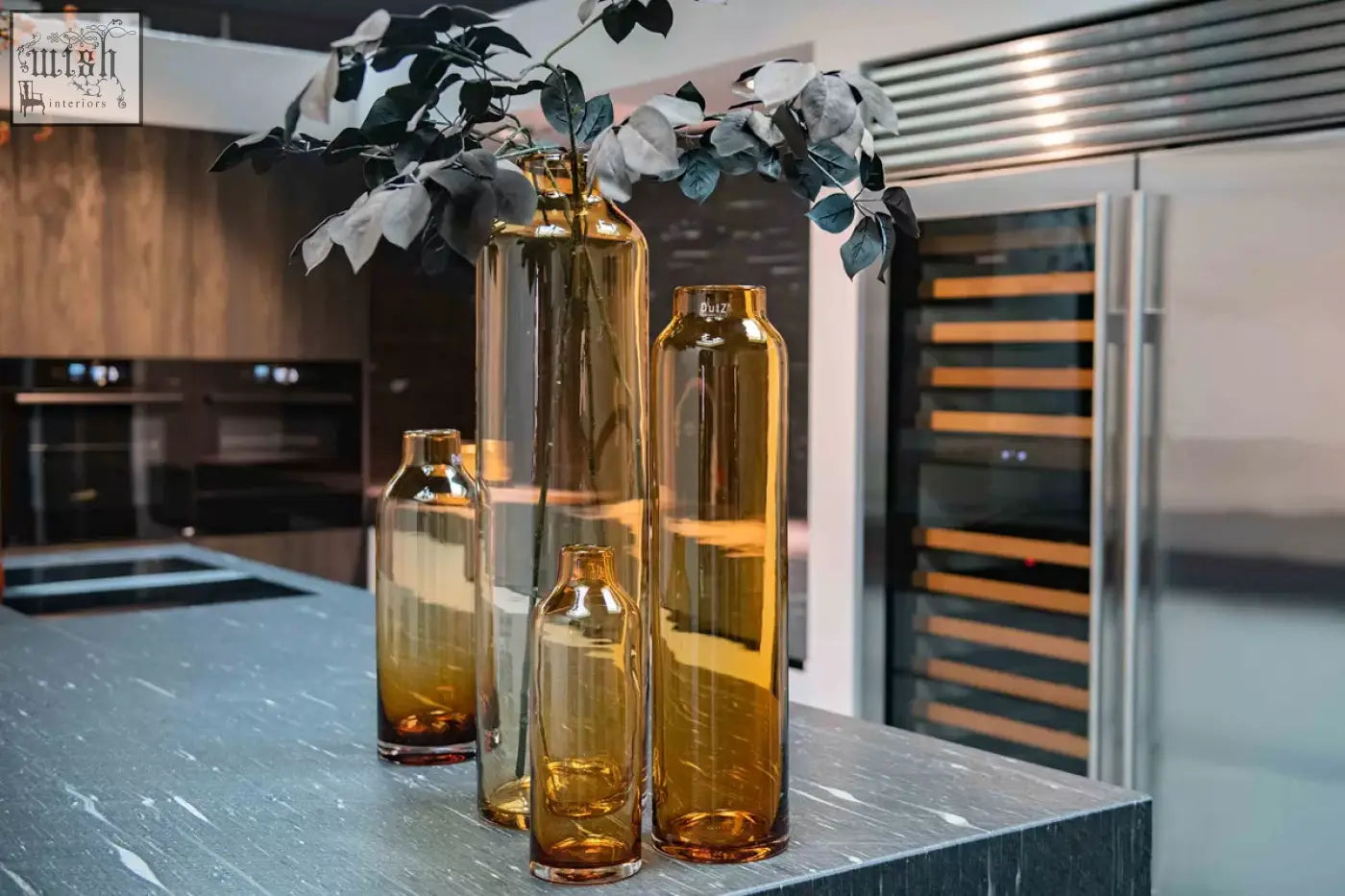Set of four mouth blown amber longo vases from dutz collection made of sleek dutz glass on dark countertop