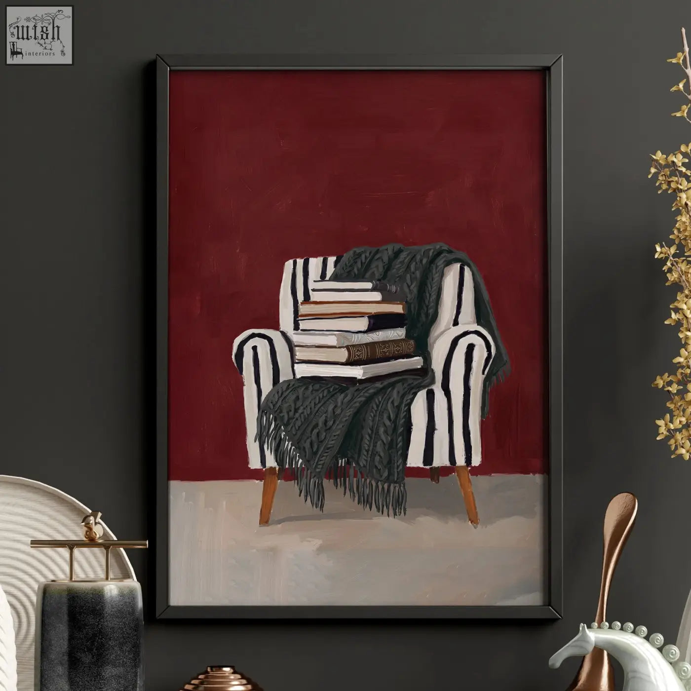 A framed burgundy lounge room wall decor print showing a black and white striped armchair with books and dark green blanket