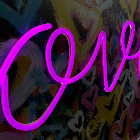 Vibrant purple neon sign spelling love with cursive lettering on colorful abstract background love solves everything