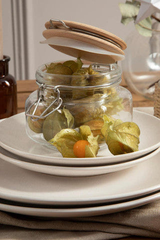 Clear luca square 800ml glass jar with wooden lid and metal clasp filled with green husks and one orange fruit