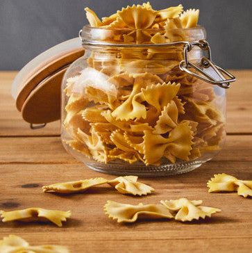 A luca square 800ml glass jar with wooden lid and metal clasp filled with golden bow tie pasta