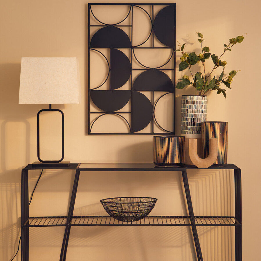 Black metal geometric wall art with circular cutouts on the lucas natural and black table lamp base