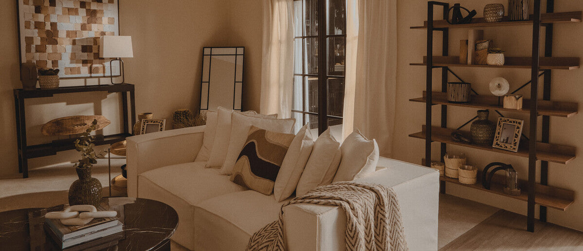 White sofa with beige and brown throw pillows and a black lucas natural table lamp beside it