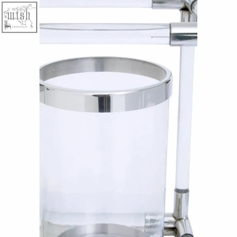 Clear acrylic trash can with polished chrome rim and base next to lucita double silver steel candle holder