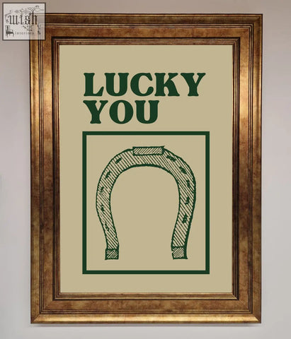 Lucky you framed wall art featuring green horseshoe illustration on off white background in rustic gold frame choices