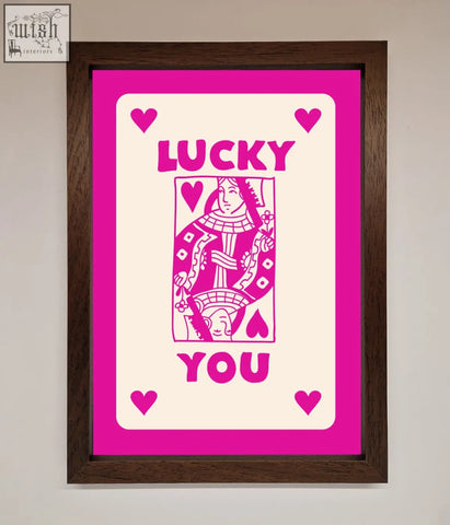 A hot pink framed poster featuring a vibrant pink and cream stylized playing card design with lucky you text