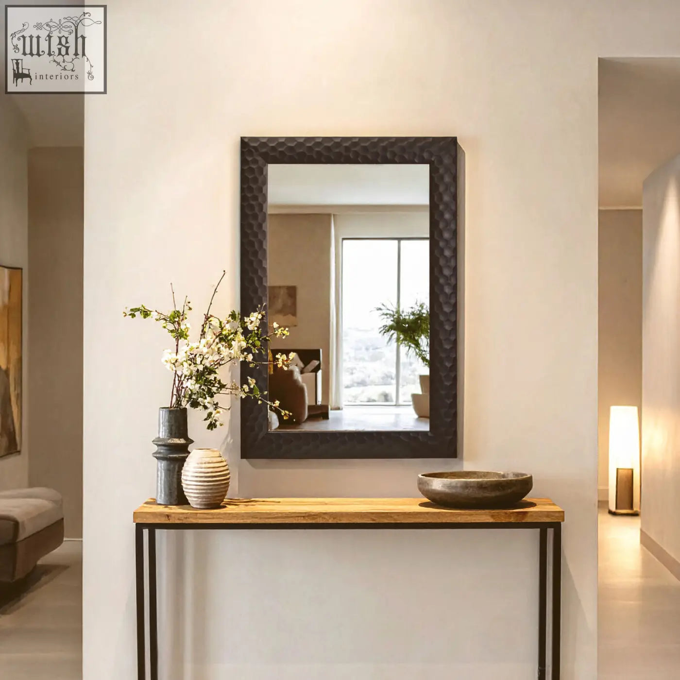 Rectangular ludlow wall mirror with black hammered metal frame mounted above wooden console table