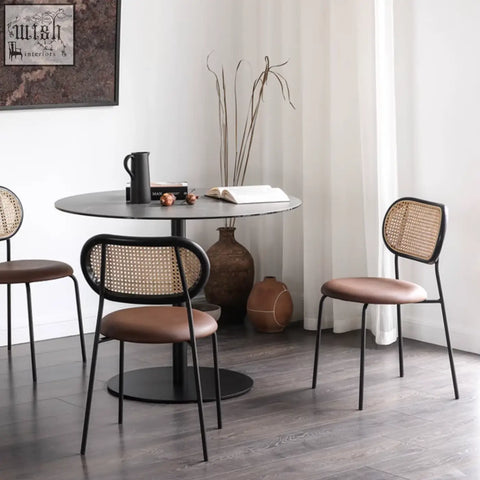 Black metal frame rattan dining chair with woven cane back and brown leather seat for stylish rattan dining
