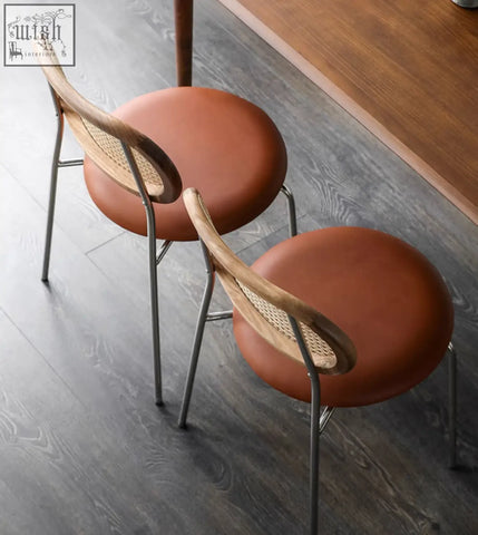 Brown leather cushioned luna rattan dining chair with woven cane back and slender metal legs in oak finish