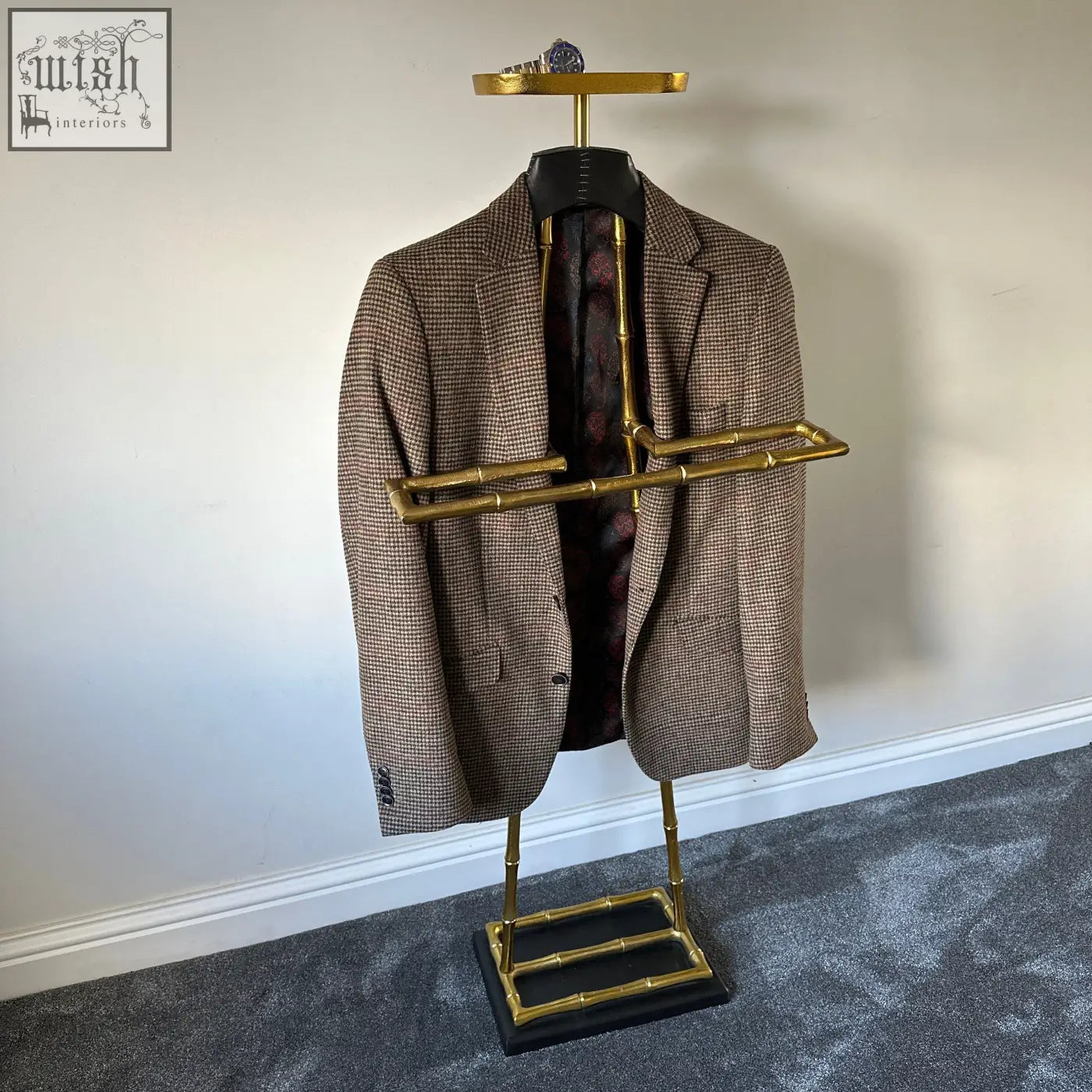 Brown houndstooth wool blazer with leather shoulder pad hanging on vintage brass gold bamboo-style coat hanger rack