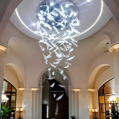 A luxury glass led chandelier with white glass panels shaped like translucent birds in a cascading design
