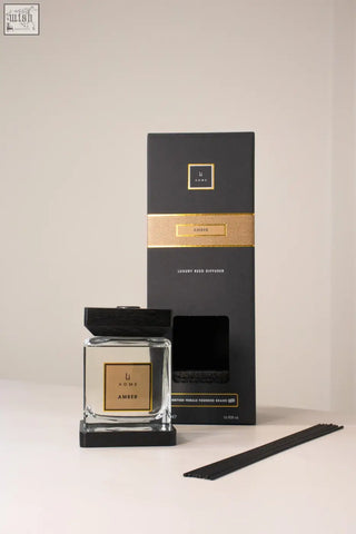 Luxury square diffuser amber with black and gold reed sticks in a clear glass bottle with amber-scented fragrance