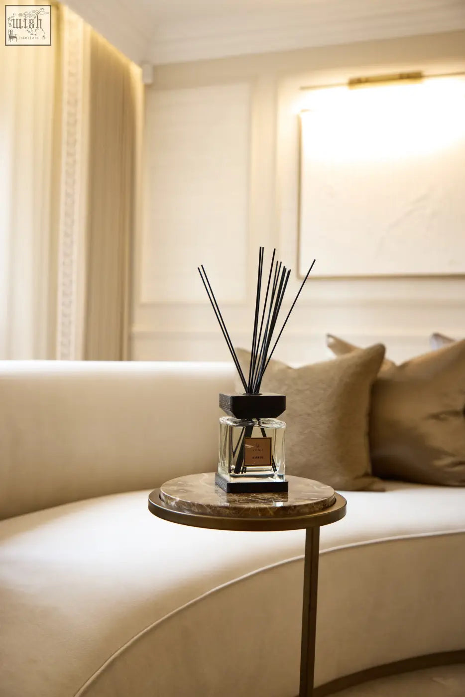 A sleek black luxury square diffuser amber with a clear glass bottle and minimalist design on a marble side table