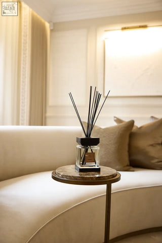 A sleek black luxury square diffuser amber with a clear glass bottle and minimalist design on a marble side table