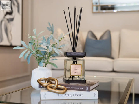 A luxury square glass reed diffuser with black reeds and dark wood base labeled li noli amber for home fragrance