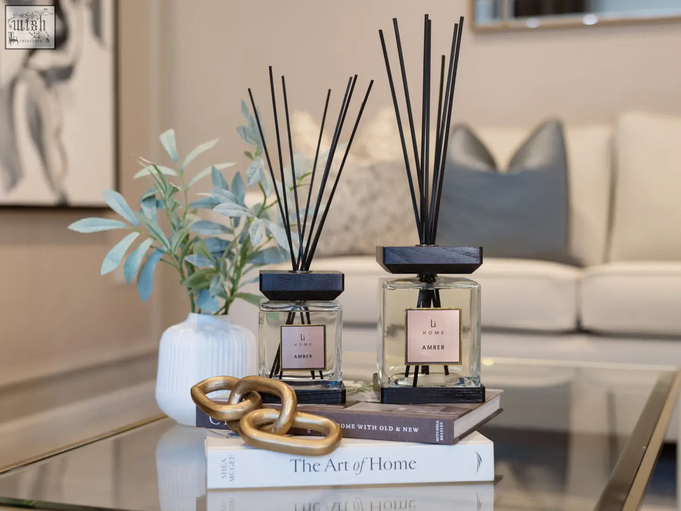 Two clear glass luxury square amber diffusers with black caps and slender reeds from li home in minimalist design