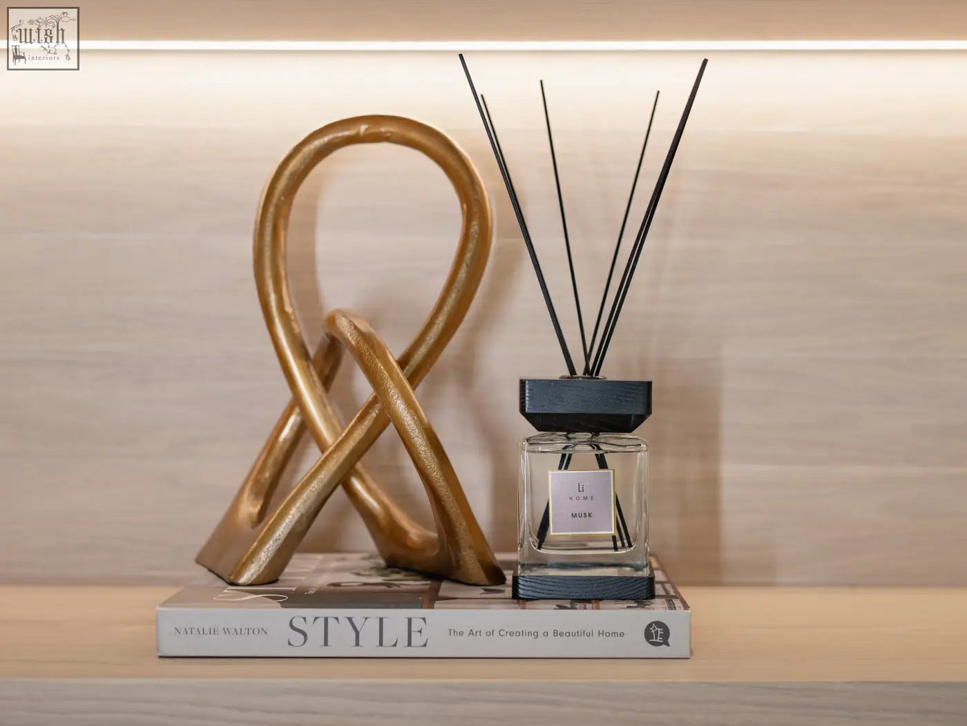 Gold metallic abstract sculpture with intertwined loops featured in luxury square diffuser musk design