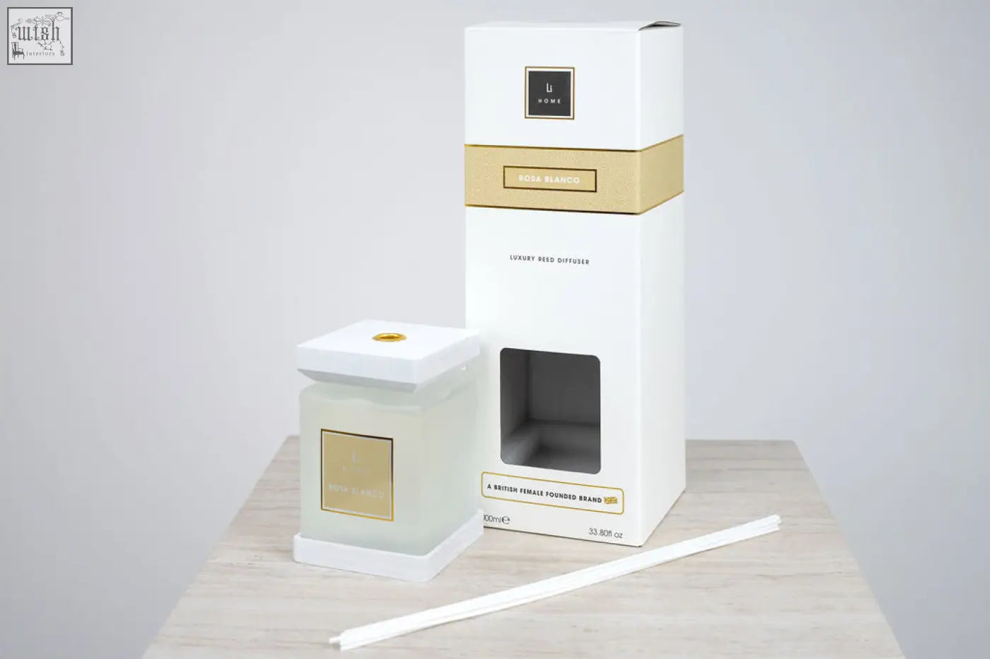 White glass reed diffuser with gold accents and matching white box labeled rosa blanca by larty luxury square diffuser rosa blanco white rose