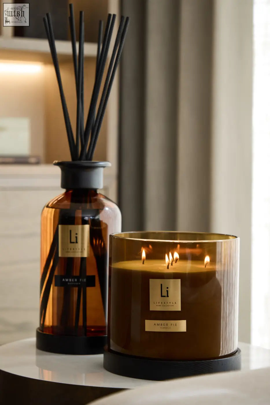 Luxury xxl amber fie scented candle in a gold rimmed glass container with three lit wicks for cozy ambiance