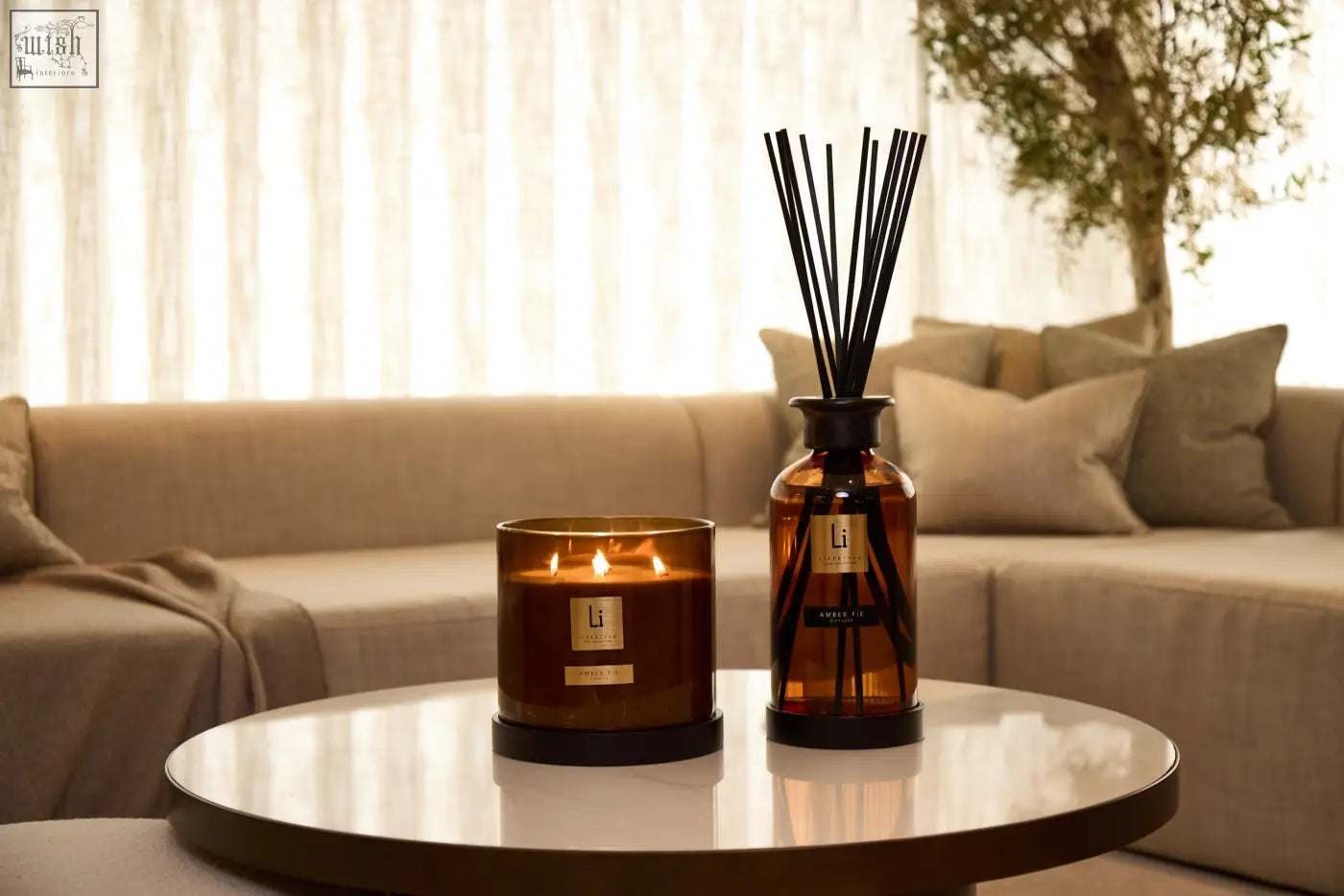 A sleek amber fie glass diffuser with black reeds and matching candle in minimalist design for luxury home scenting
