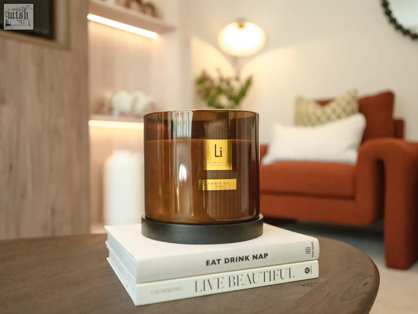 A sleek amber glass luxury xxl candle amber fie with gold label sitting on two white books