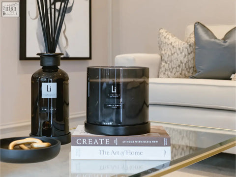 Black glass diffuser with slender reeds and minimalist label next to sable onyx luxury xxl candle holder