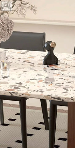 Black abstract figurine with gold sphere accent on head displayed on lynette terrazzo dining table surface