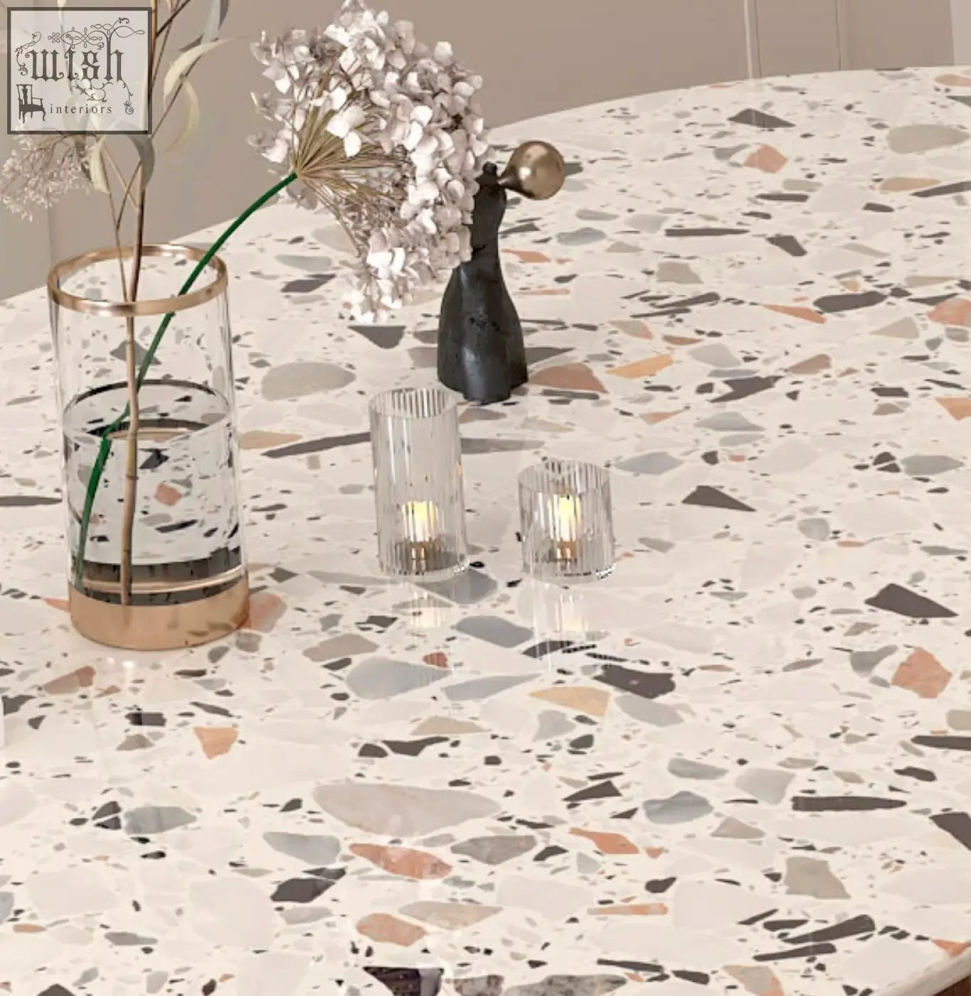 A clear glass vase with gold rim and white flowers on a lynette terrazzo dining table centerpiece