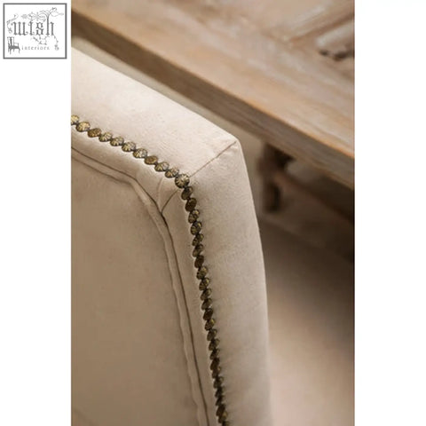 Beige linen dining chair with decorative brass nailhead trim and oak wood whitewash finish for dining room use