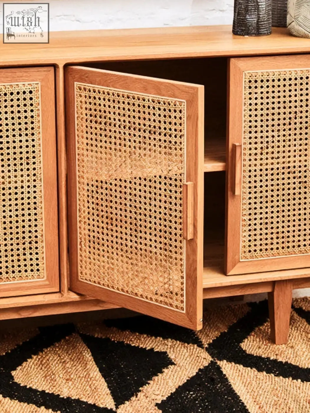 A light oak wood door sideboard with lyon rattan woven cane panels and one open door showing an empty shelf