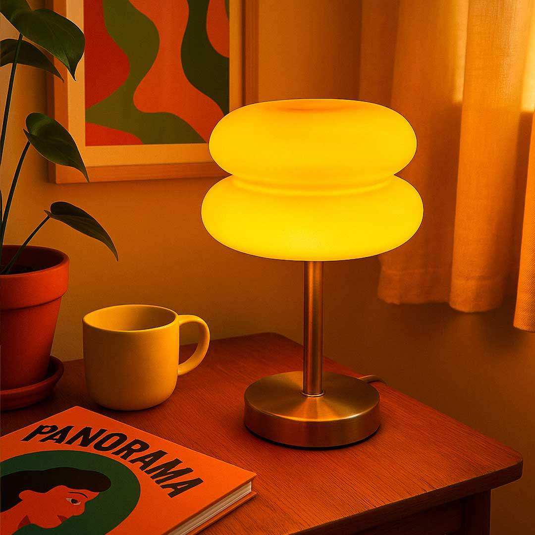 A warm yellow macaron glass table lamp with frosted glass shade and sleek brass base perfect for cozy lighting