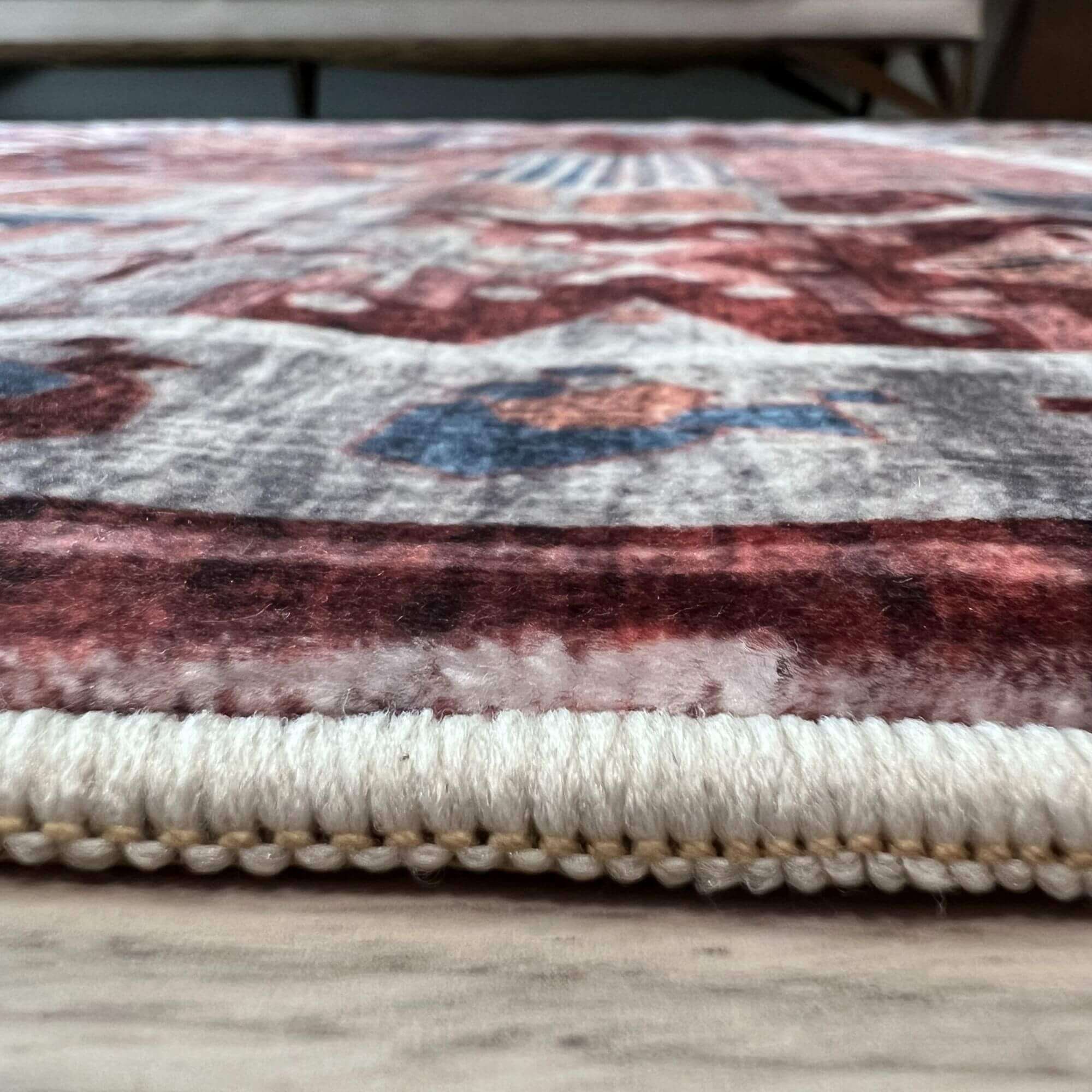 A madar vintage washable rug with plush red and blue pattern on faded white and cream fringe edges
