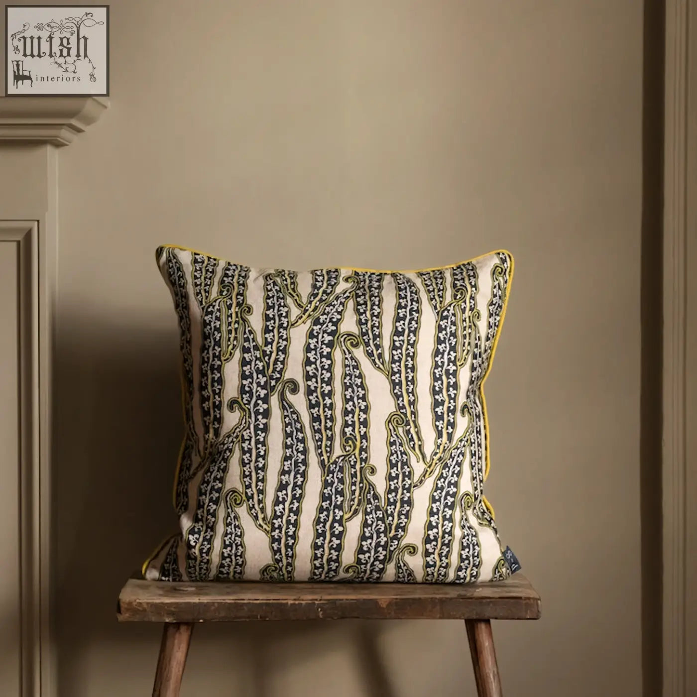 Cream-colored magic beans cushion with bold black and green vine pattern and bright yellow border