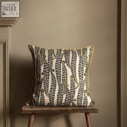 Cream-colored magic beans cushion with bold black and green vine pattern and bright yellow border
