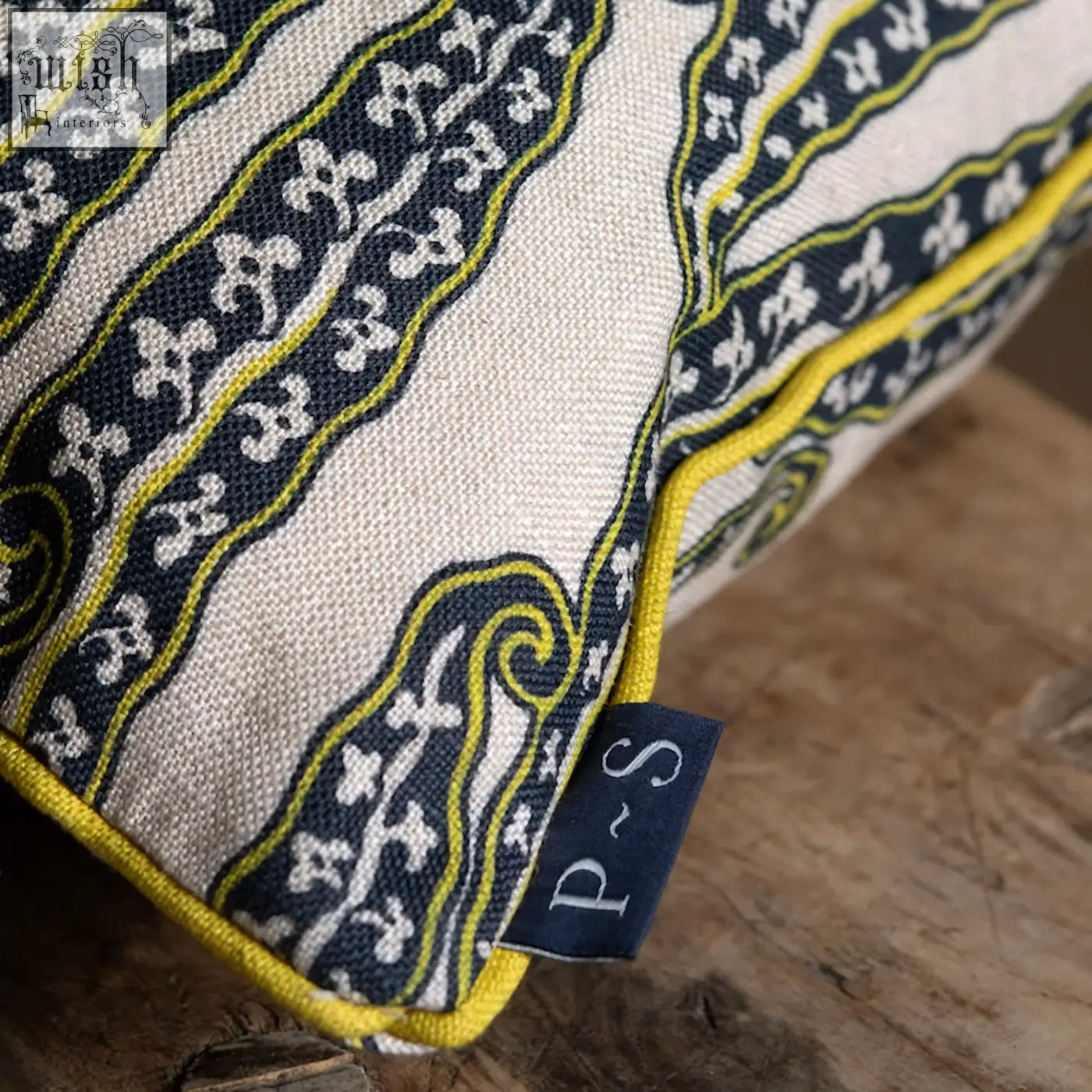 A cream magic beans cushion with navy blue and yellow paisley patterns and a yellow stitched border