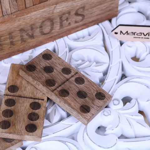 Two light brown wooden dominoes with dark pips on an ornate white surface from the mahua wooden domino set
