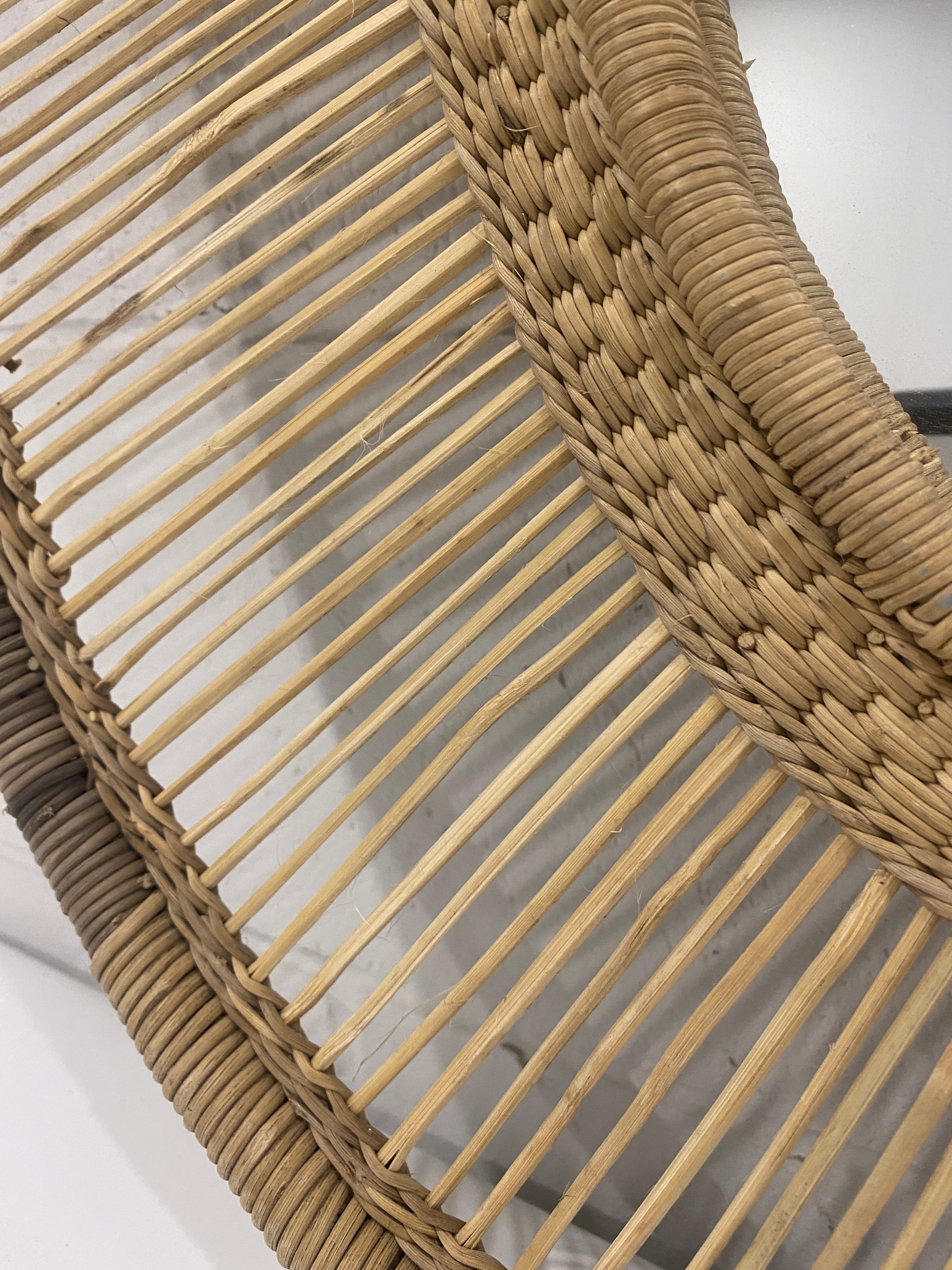 Natural woven rattan chair frame with curved interlaced design shown in the back of malawi mirror oblong large