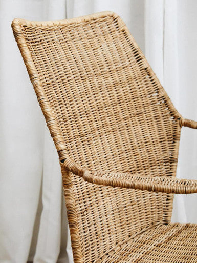 A light brown manado angled design natural rattan chair with a woven geometrically patterned backrest and armrests