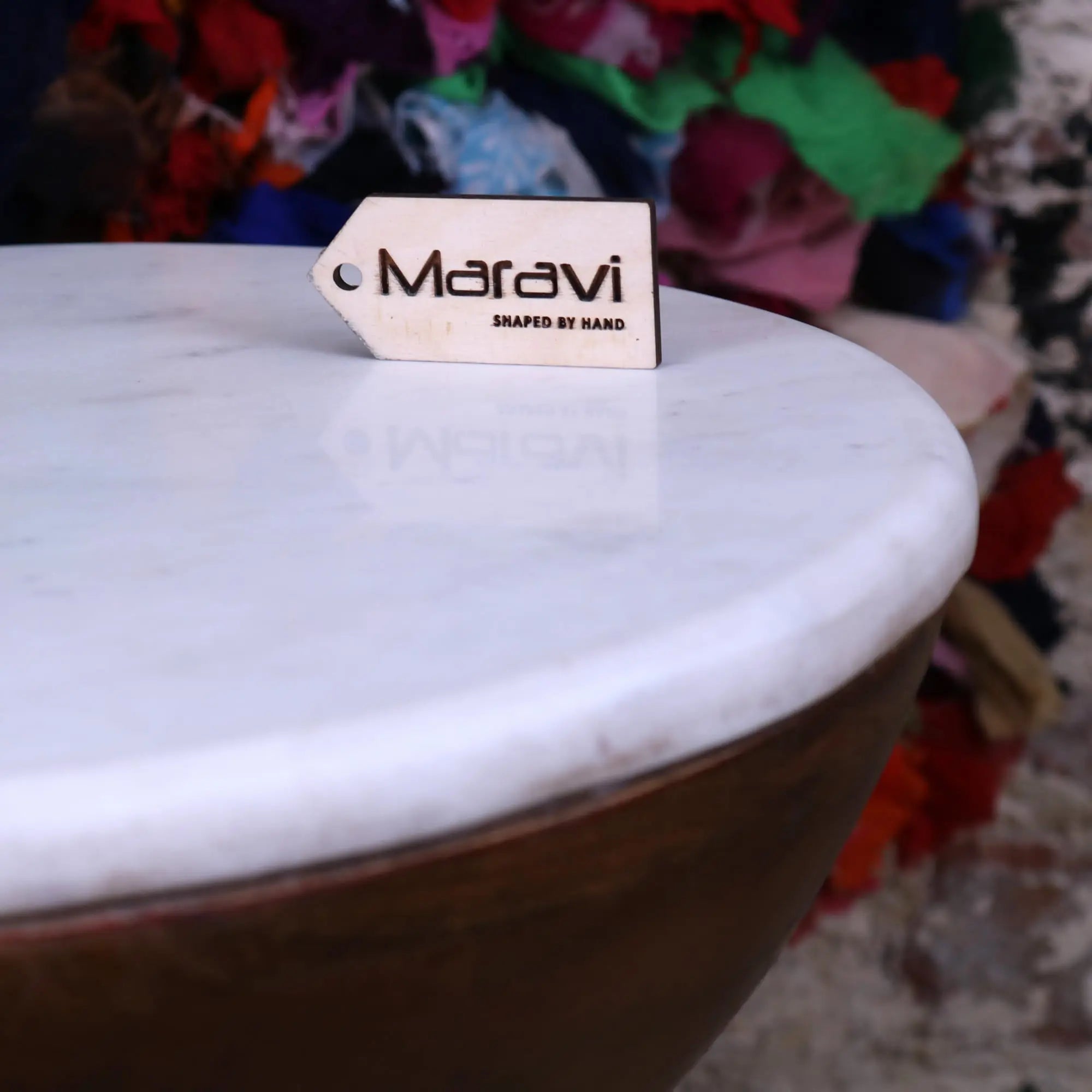 White wooden tag engraved with maravi and shaped by hand on mandawa mango wood and marble side table