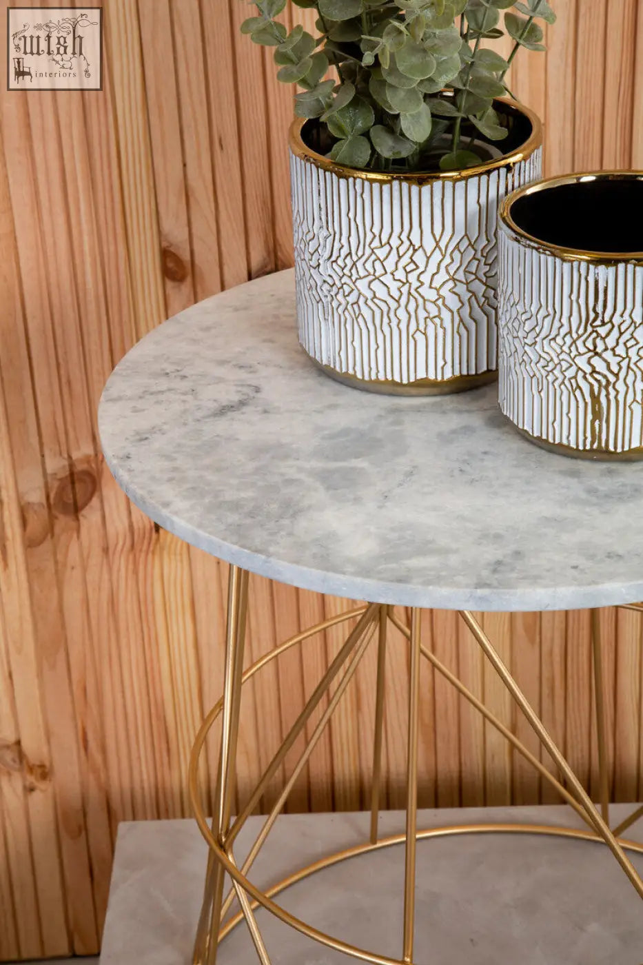 White marble round side table with white ceramic planters featuring gold rims and eucalyptus plants
