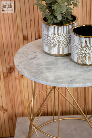 White marble round side table with white ceramic planters featuring gold rims and eucalyptus plants